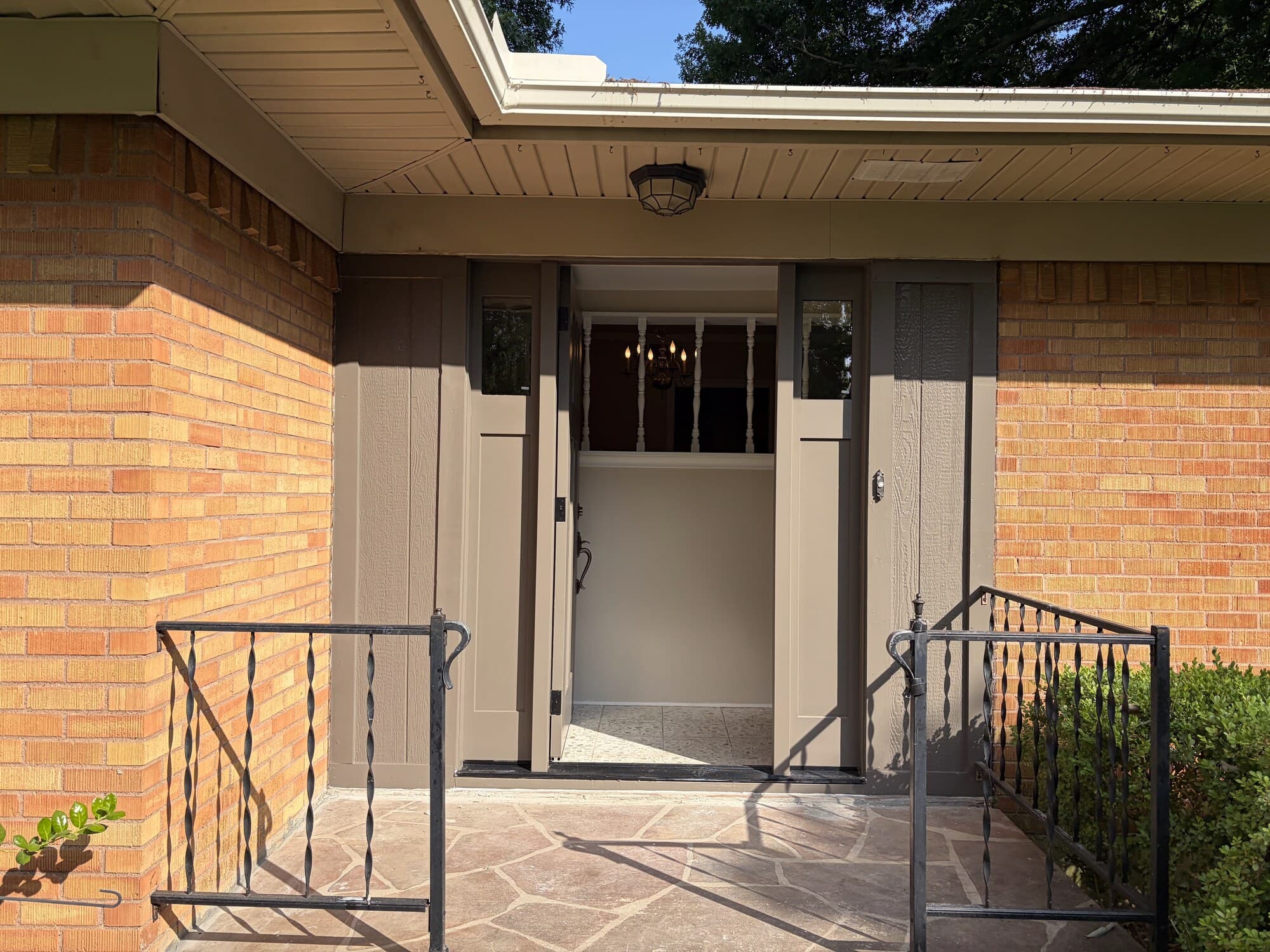 A new front door standing open, seen from a covered porch with wrought-iron railings