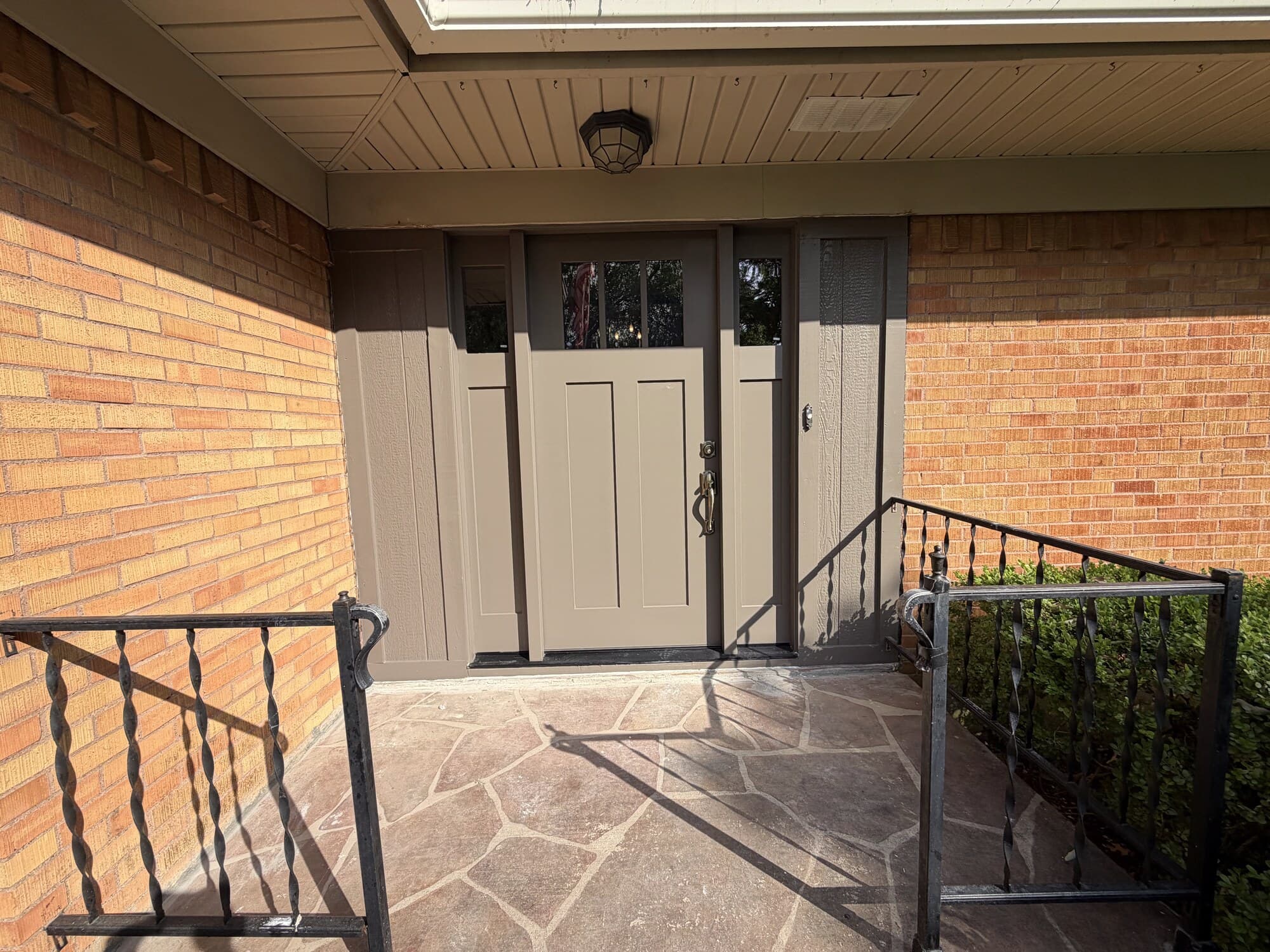 Front door and sidelights closed, seen from the porch with the brick wall and iron railing