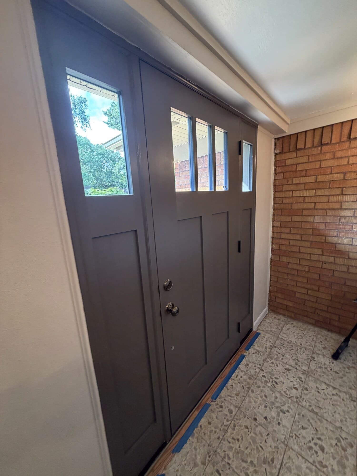 Interior view down the entry hall toward the new door, brick wall on the right