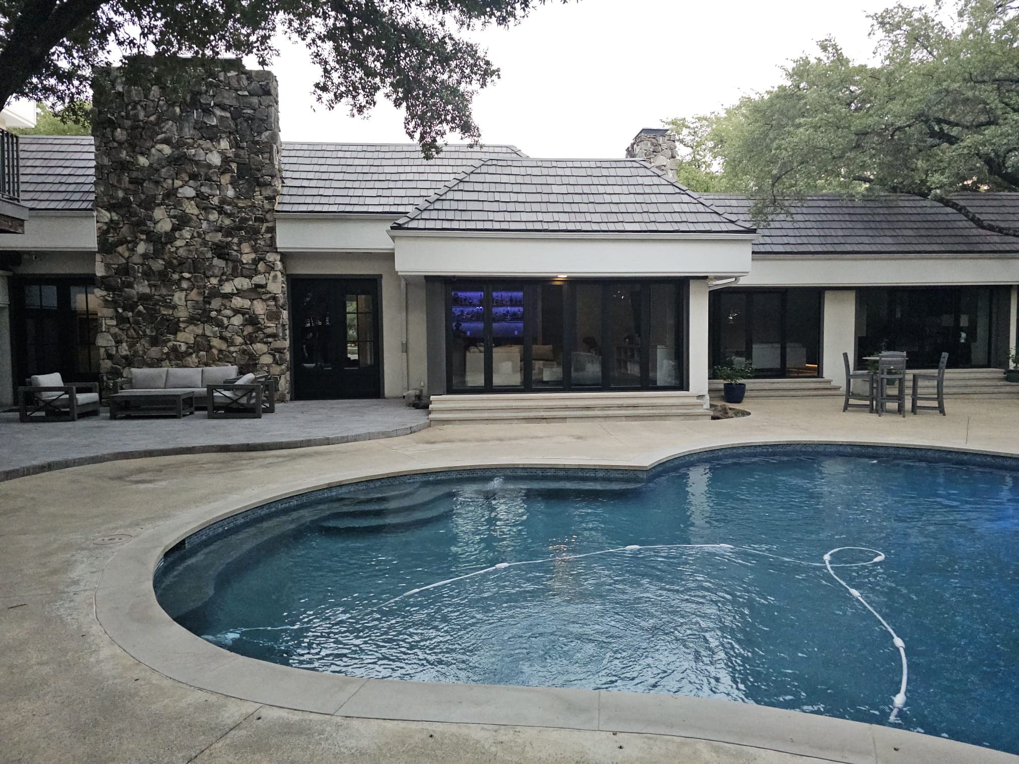 Wide view of the rear elevation across the pool, showing the installed door systems along the back of the house